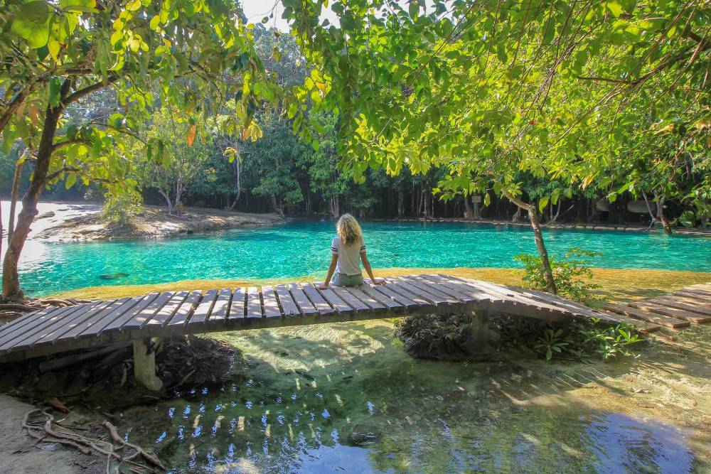 Uma garota sentada ao lado da Piscina Esmeralda (Sa Morakot) em Krabi