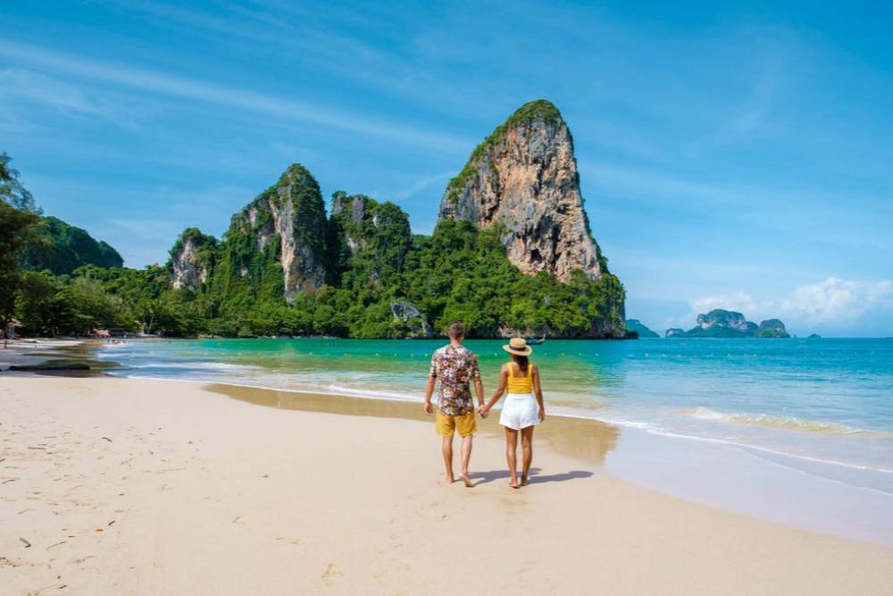Um casal caminha na praia de Railay Beach, Krabi