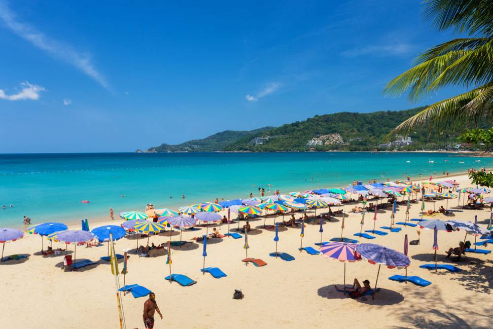 Turistas relaxam sob guarda-sóis na praia de Patong, em Phuket