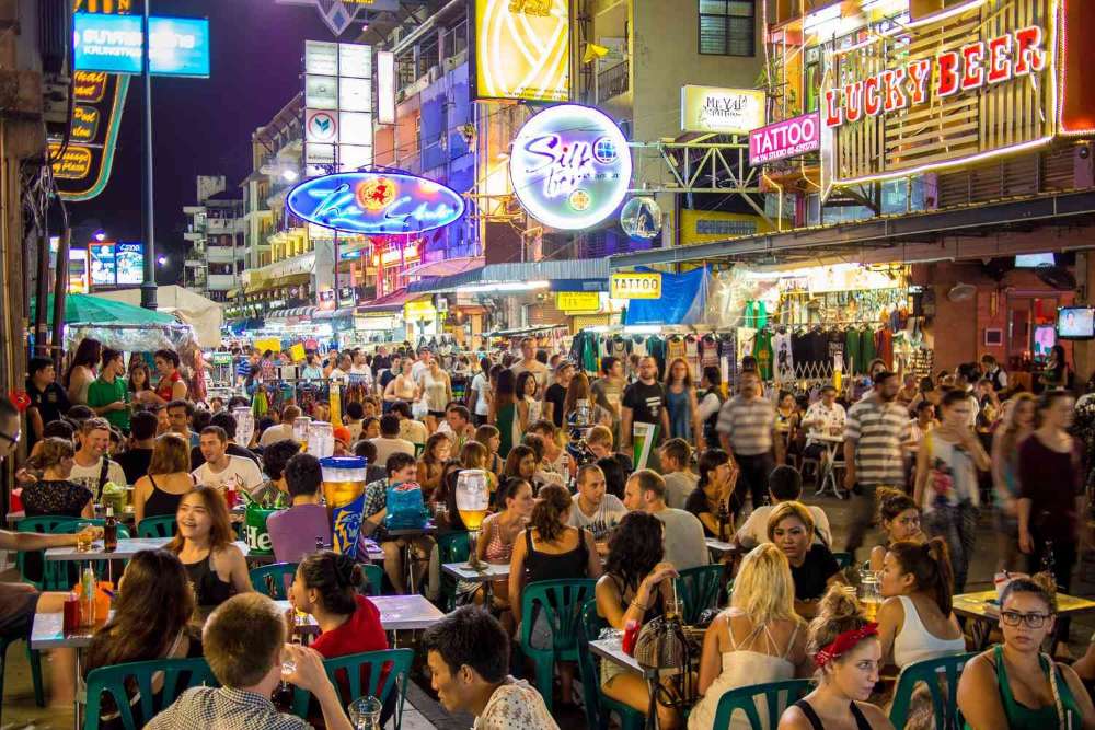 Uma barraca de rua cheia de turistas na Khao San Road, Tailândia, à noite